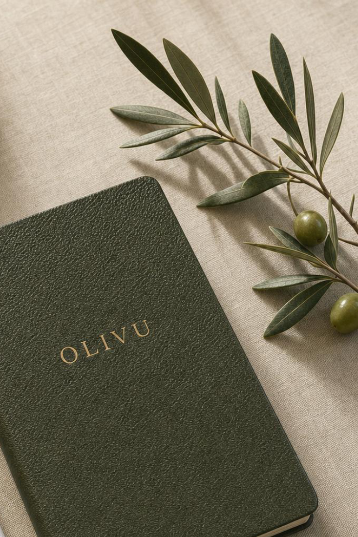 The Olivu journal resting on linen beside an olive branch